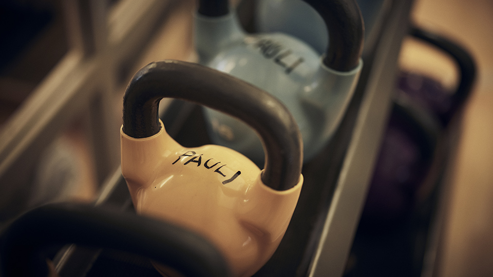 Flera kettle bells ligger på rad i skolans gym.