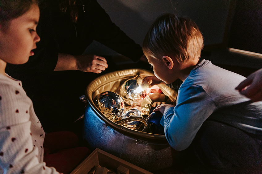 Med små lampor lyser barnen upp de gnistrande skatterna i det nedsläckta rummet.