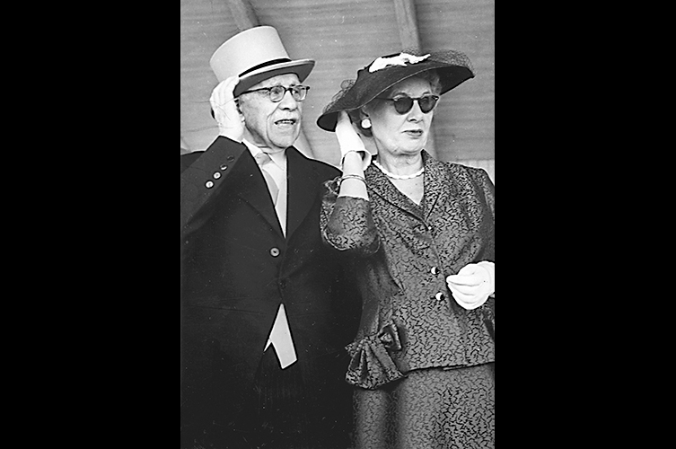 Axel och Eva Cronquist
står högtidsklädda och följer travtävlingar på Jägersro travbana i Malmö 1958. Foto:
Okänd fotograf / Malmö Museer.