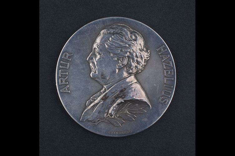 Fotografi på en minnesmedalj i silver. På medaljen syns en man i profil och namnet Artur Hazelius. 