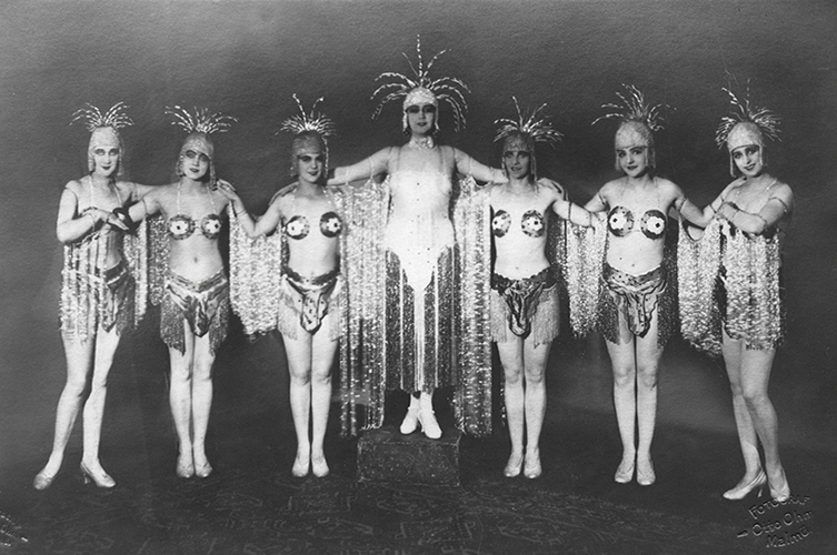 7 operettsångerskor poserar i sina teaterdräkter. 