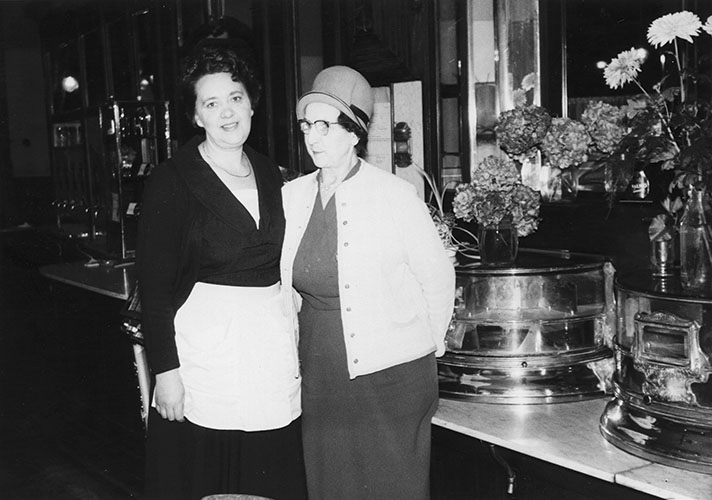 Äldre foto på två kvinnor i kafémiljö.