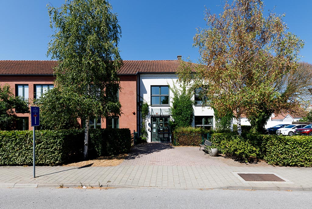 Två björkar på varsin sida om ingången till den vitmålade fasaden.