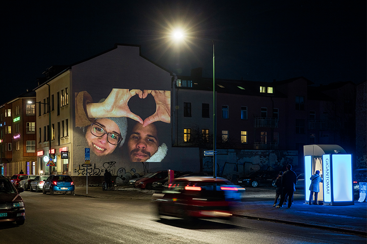 En projektor lyser upp en fasad i Östra Sorgenfri. Projektionen visar två personer som med sina händer formar ett hjärta.