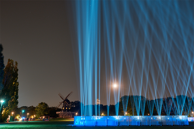 En ljusinstallation vid Mölleplatsen som sänder ut blått ljus mot himlen på en rad.