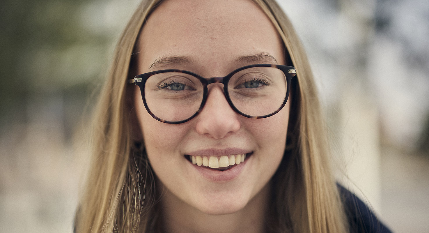 En leende ung kvinna med långt ljust hår och glasögon.