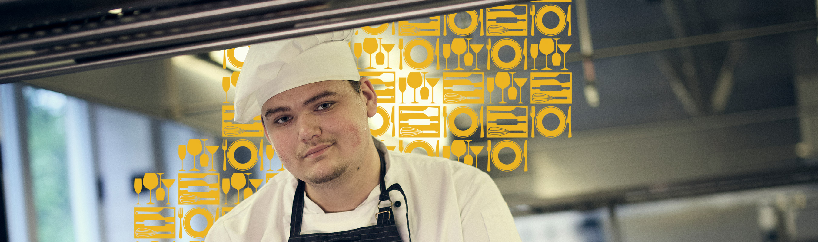 Elev i kockläder och kockmössa i restaurangköket.
