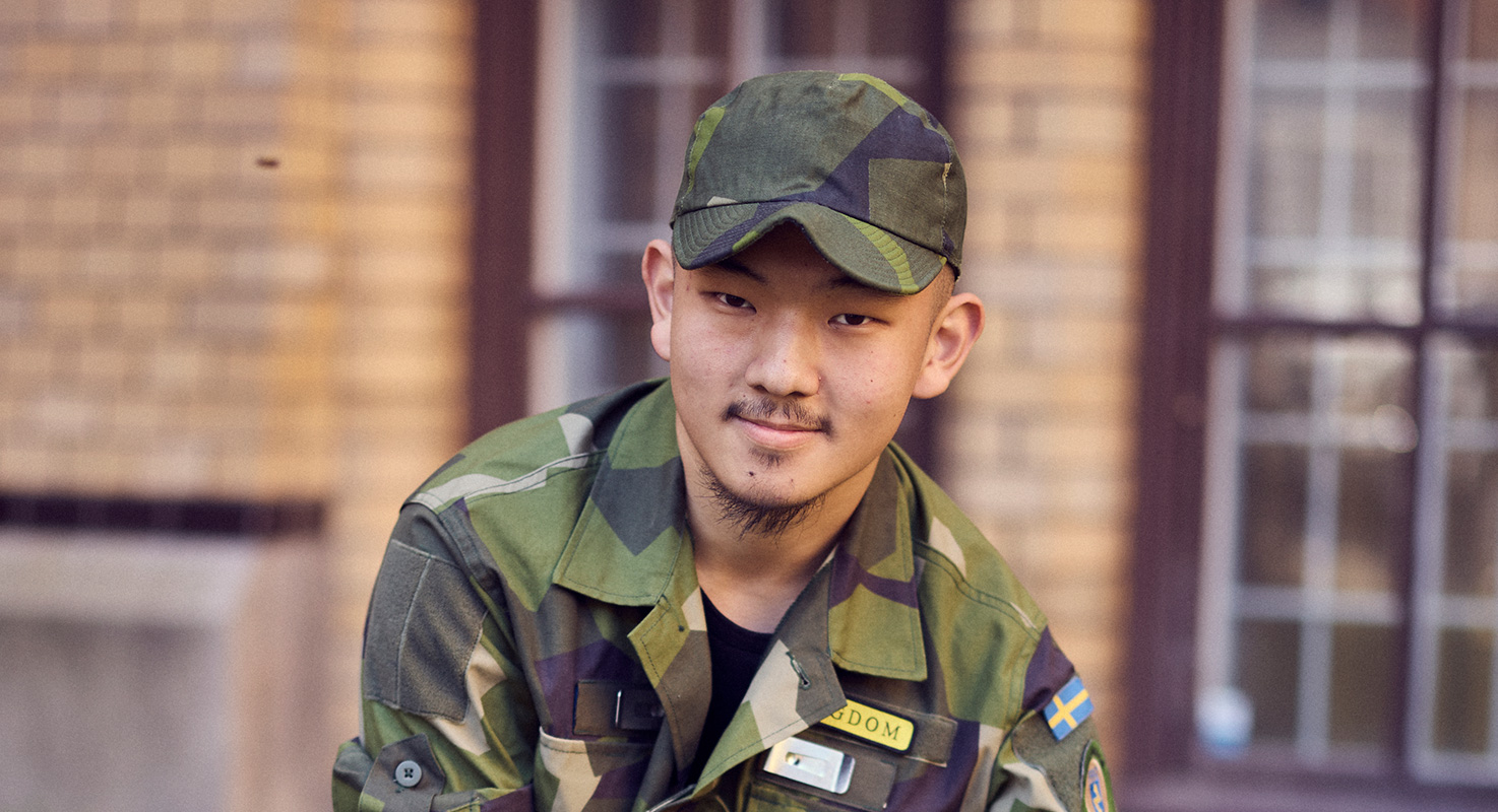 Elev i militäruniform framför skolbyggnaden.