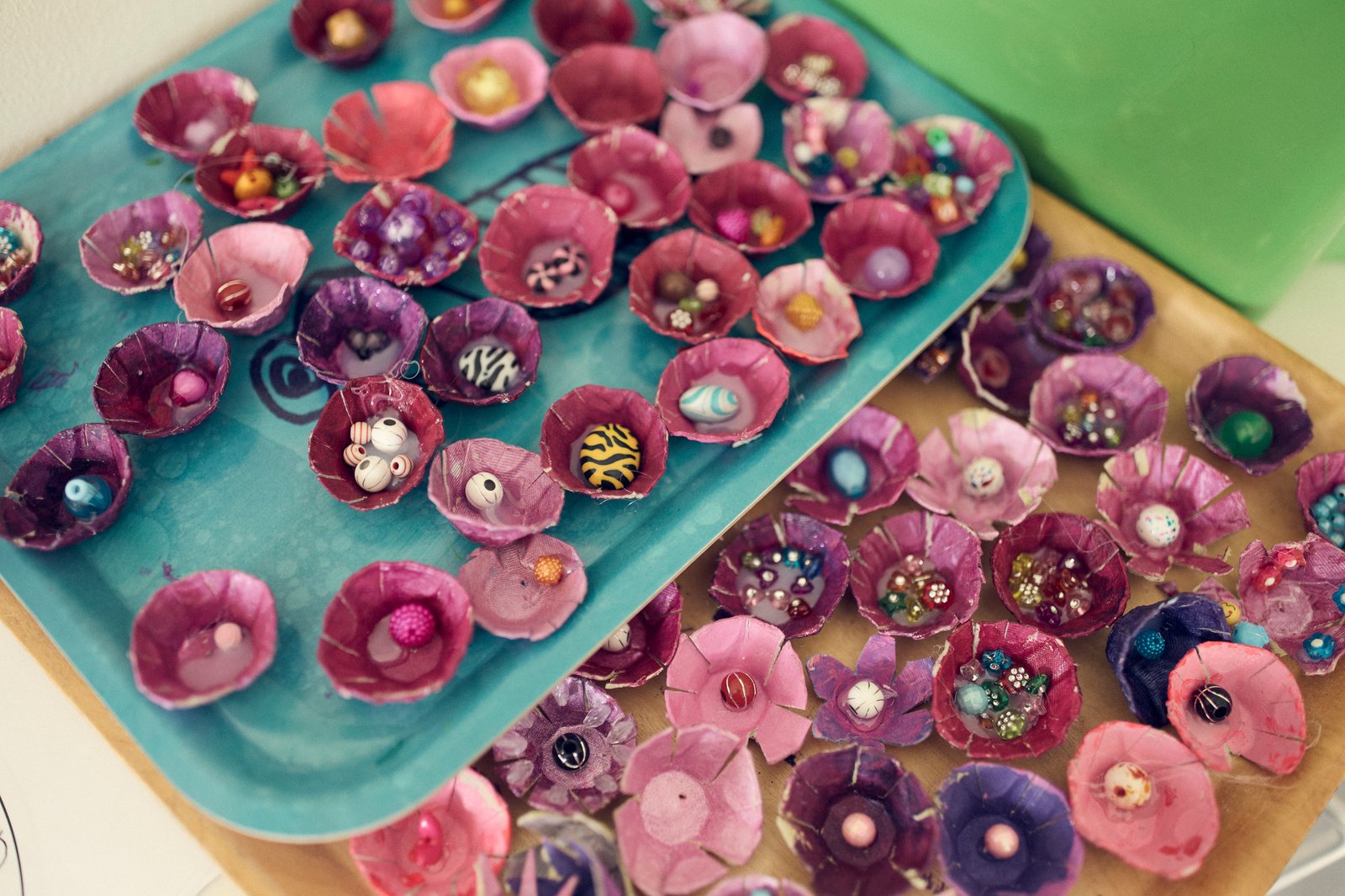 Brickor med pyssel som ska föreställa rosa och lila snäckor med pärlor i. 