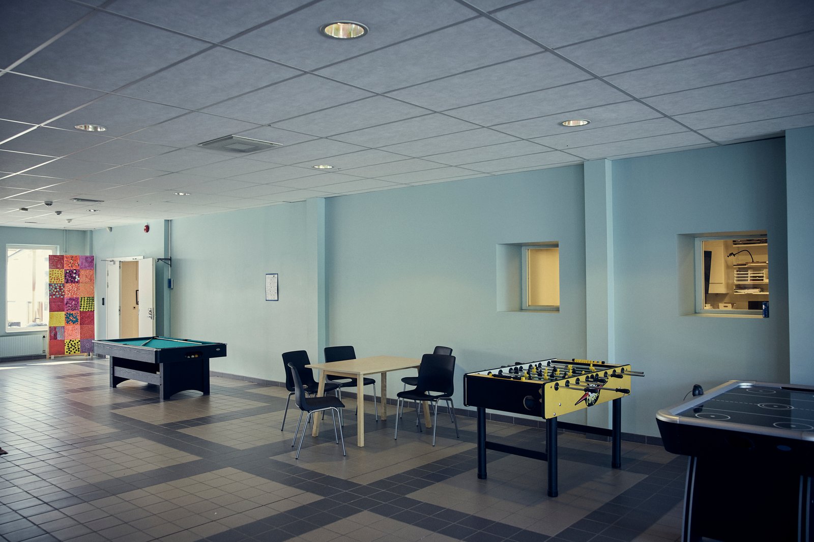 En korridor med pingisbord, biljard och bord med stolar.