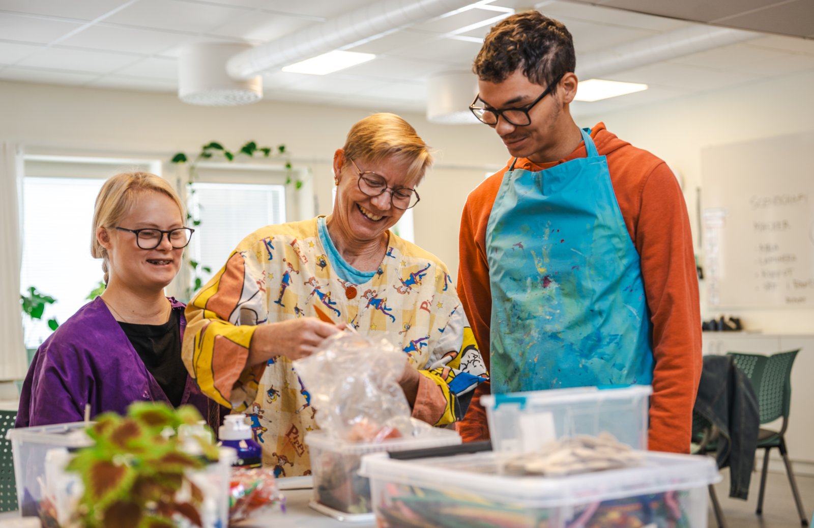 En lärare och två elever arbetar tillsammans med ett kreativt projekt. 