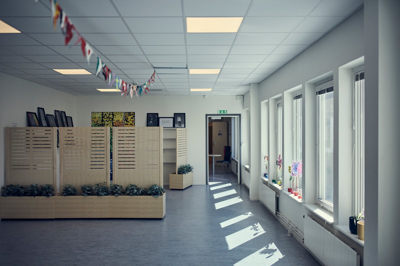 Visar en korridor med vimplar i taket och fönster längs ena sidan.