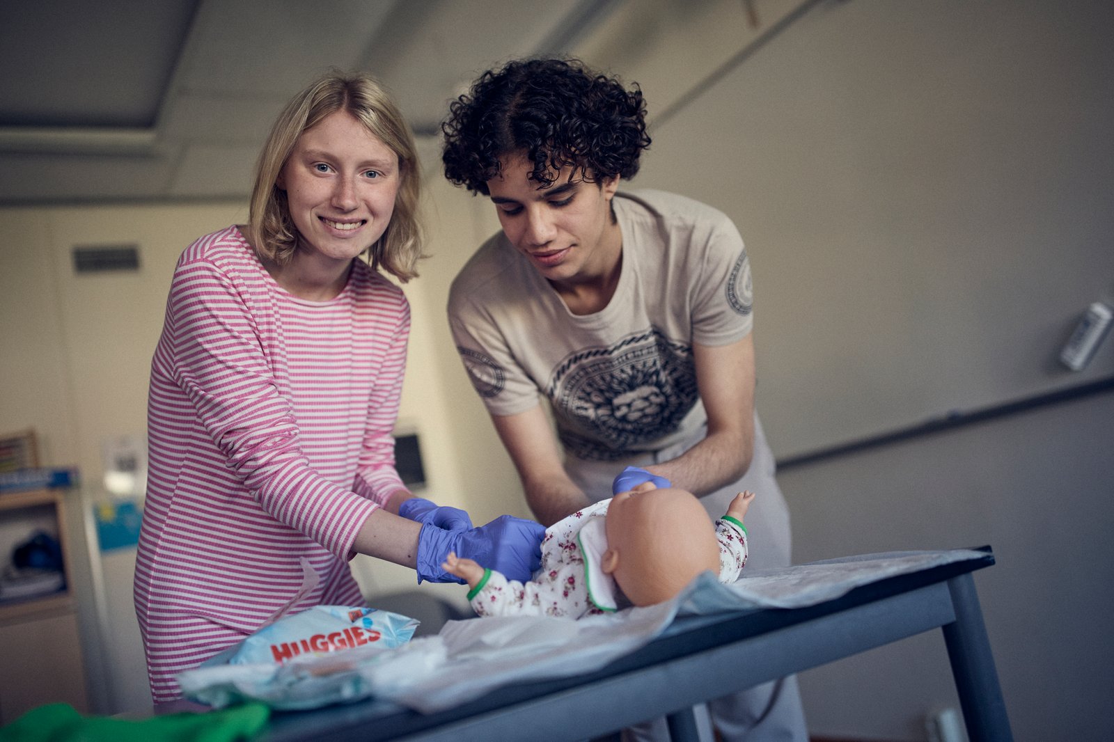 Två elever står framför ett bord där det ligger en docka. 