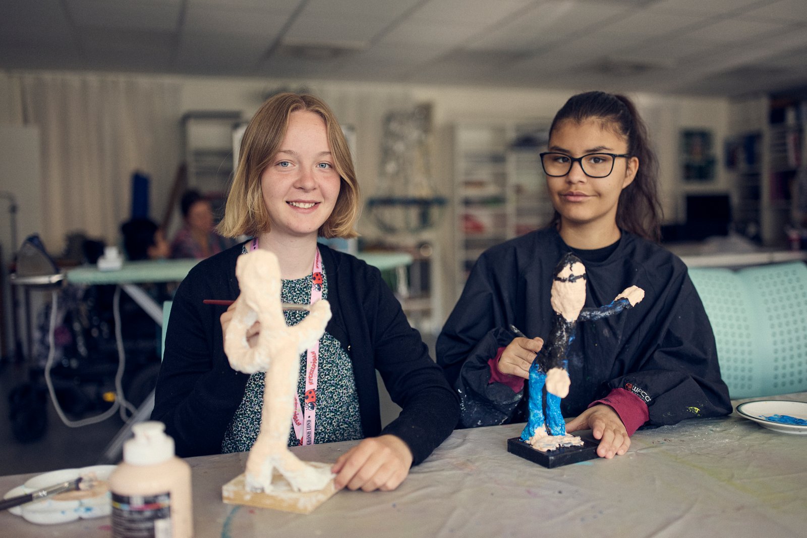 Två elever visar upp sina konstverk. 