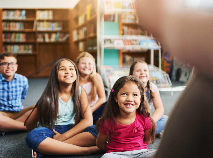 Bild på barn som lyssnar på saga i ett bibliotek. 