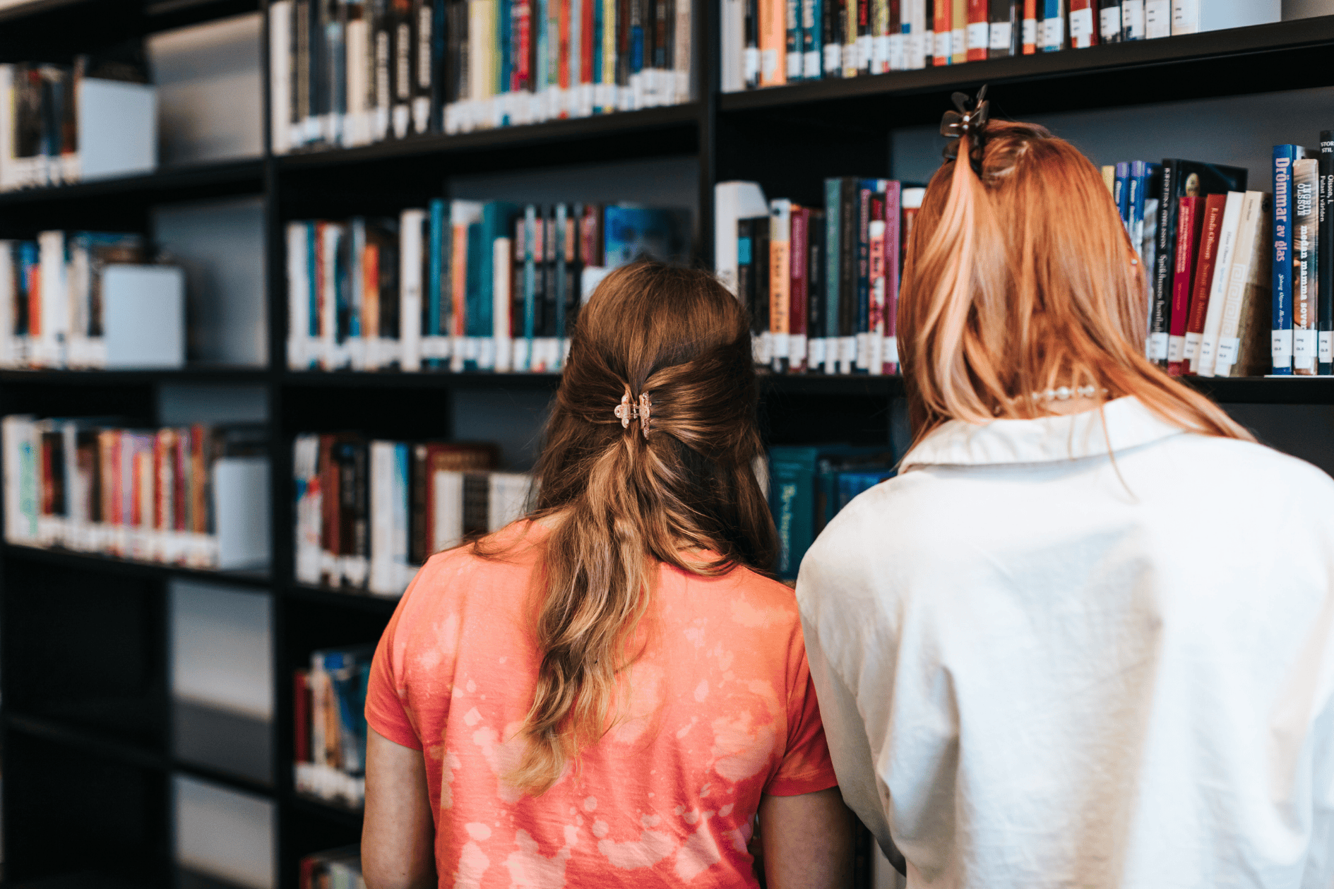 Två personer står vid en bokhylla och tittar på böcker.