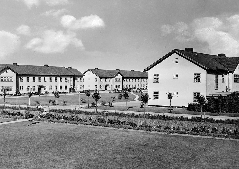 Tidstypiska vårdbyggnader som ligger på rad med nyanlagda gräsmattor framför