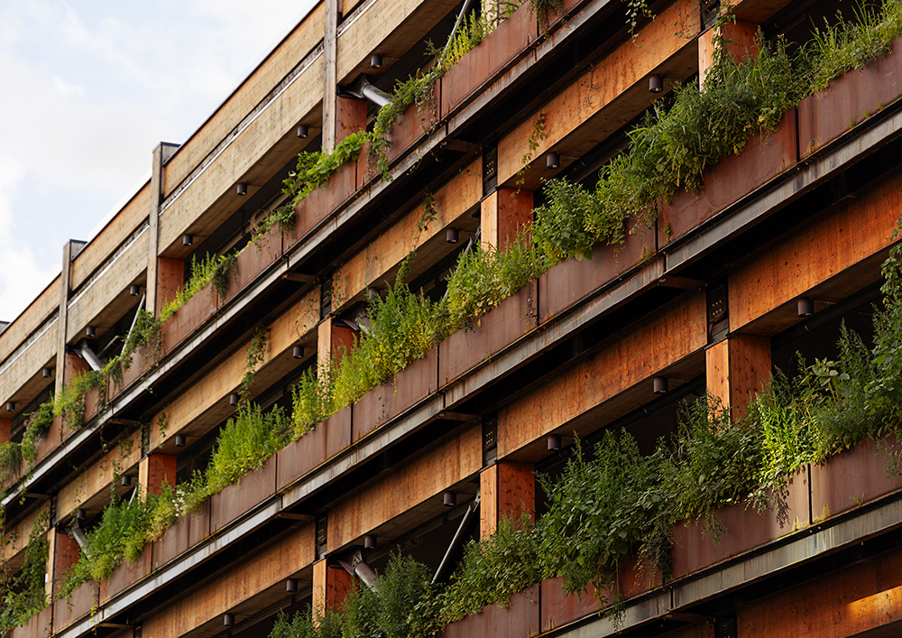 Närbild på mobilitetshusets fasd med växter på varje våningsplan