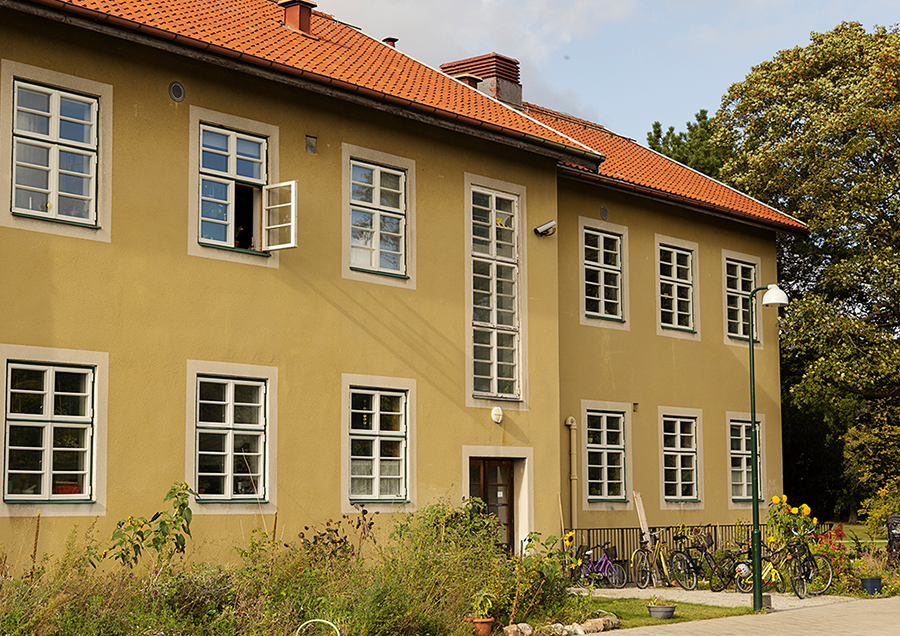 Gult hus på grön gräsmatta. I bakgrunden blå himmel.