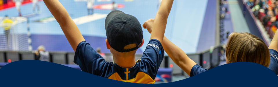 Foto på två unga personer som hejar på Sveriges landslag i handbolls-VM 2023.