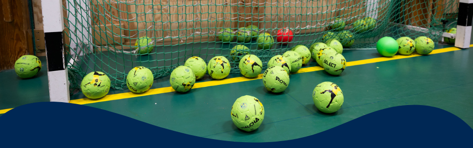 Foto på flera handbollsbollar som ligger i ett mål.