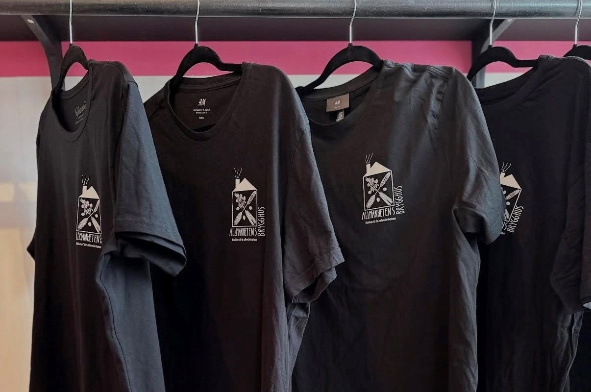 Svarta cirkulerade t-shirts med nytt tryck hänger på en klädstång.