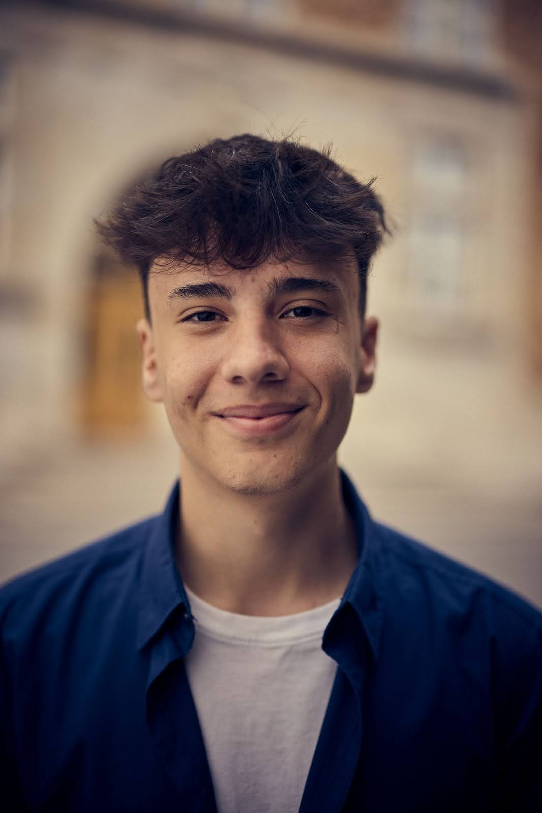 Filip i mörkt hår och blå skjorta utanför skolan.