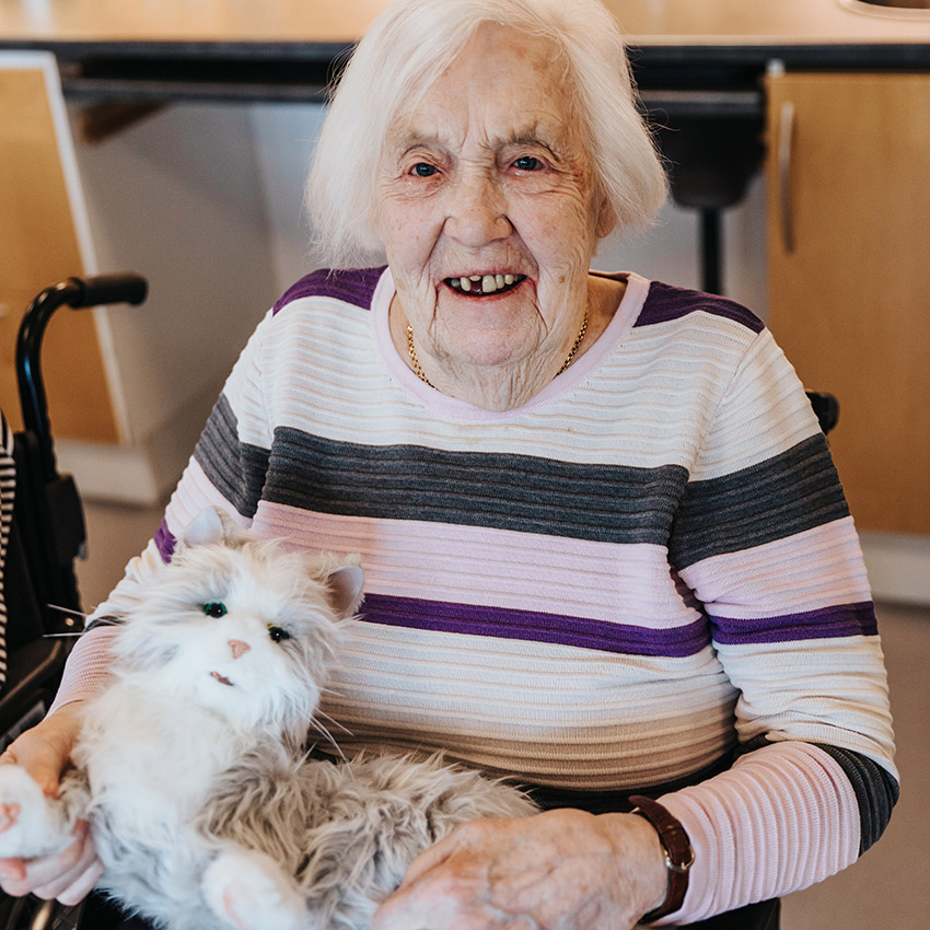 Inga-Lisa har vitt hår och en randig tröja. Katten är vit och grå.