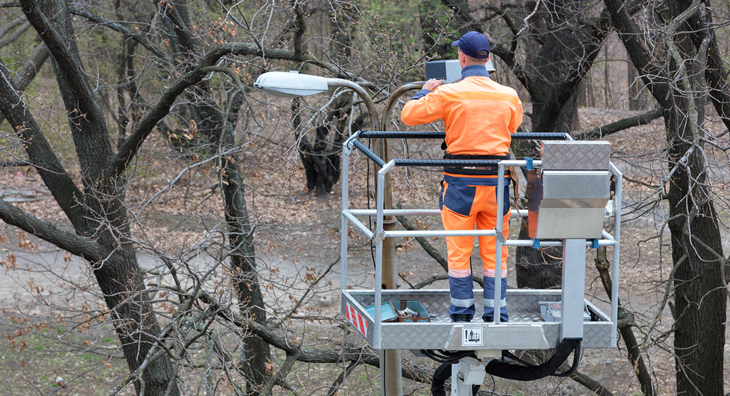 Elektriker i en lyftkran reparerar en lyktstolpe.