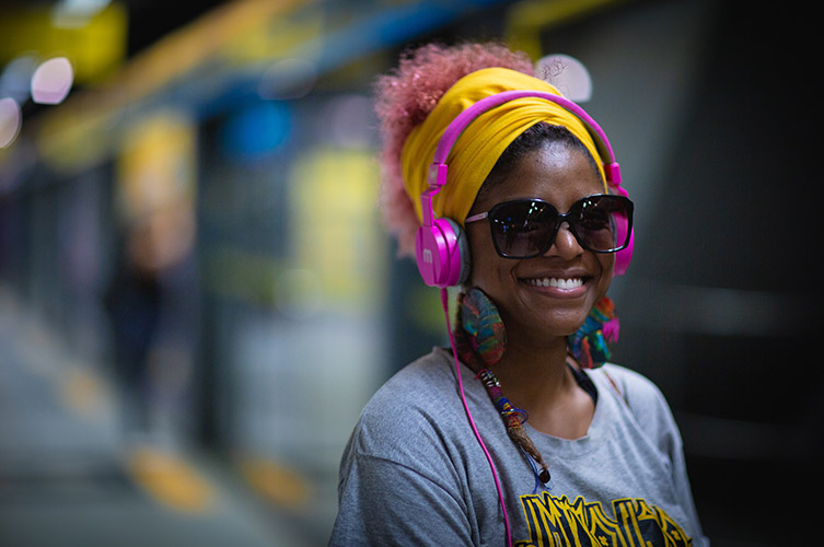 Kvinna i stora solglasögon med rosa hörlurar.