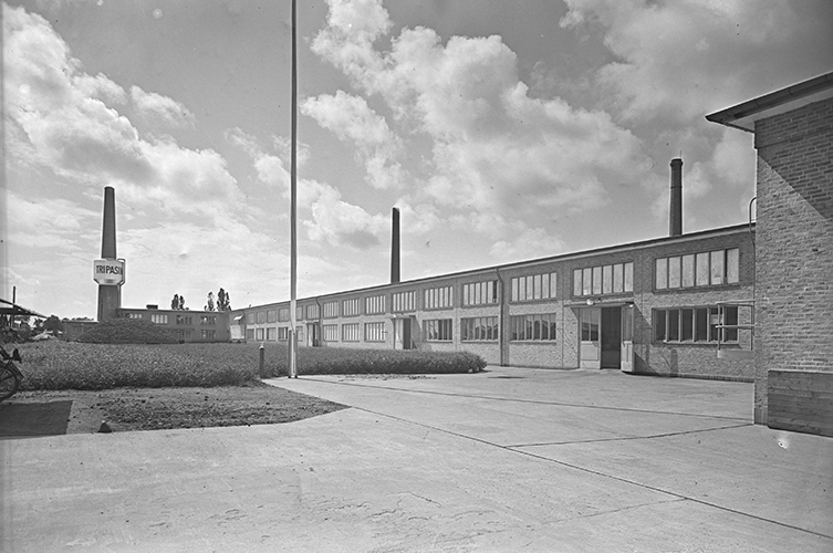 Äldre fotografi på fabriksbyggnadens fasad. Byggnaden är i tegel och har skorstenar.