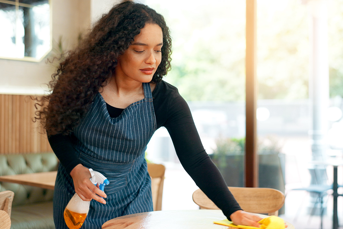 Medarbetare i restaurang rengör bord i matsalen inför dagens gäster.
