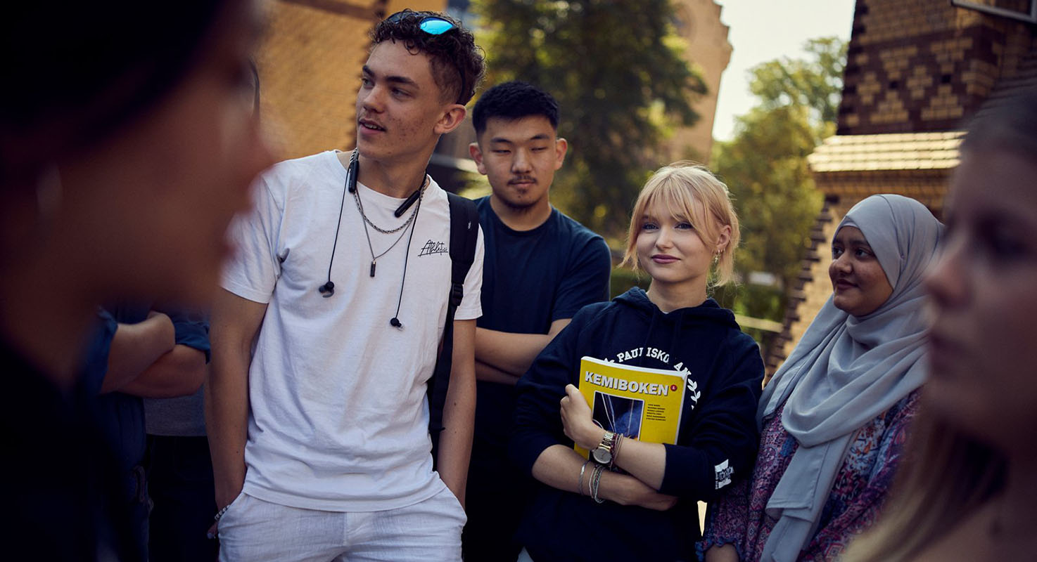 En grupp elever pratar med varandra ute på skolgården.