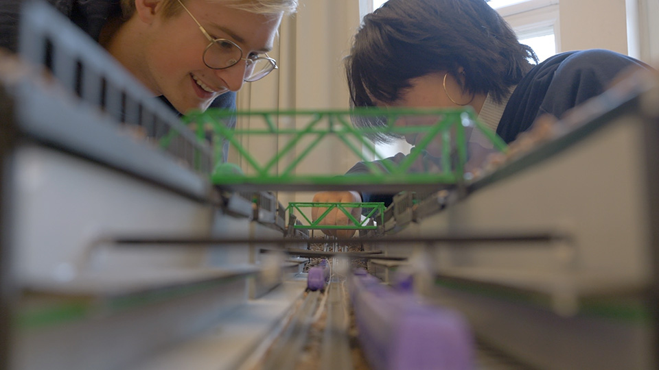 Två elever arbetar med en modell över en byggnad.