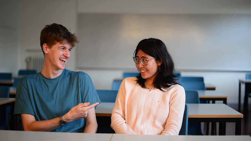 Två glada elever sitter i ett klassrum