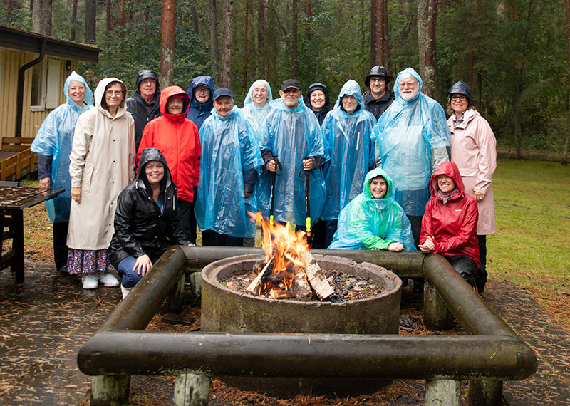 Kollo-gruppen har samlats i regnkläder utanför stugan framför en brasa.