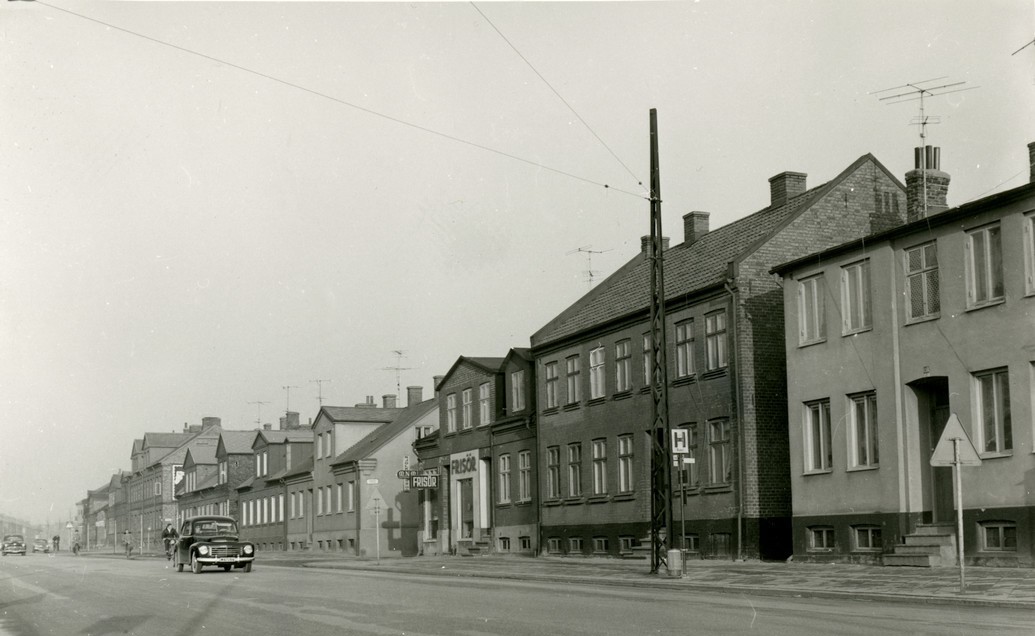 En gammal svartvit bild av en gata med hus, som fångar en nostalgisk atmosfär från en svunnen tid.