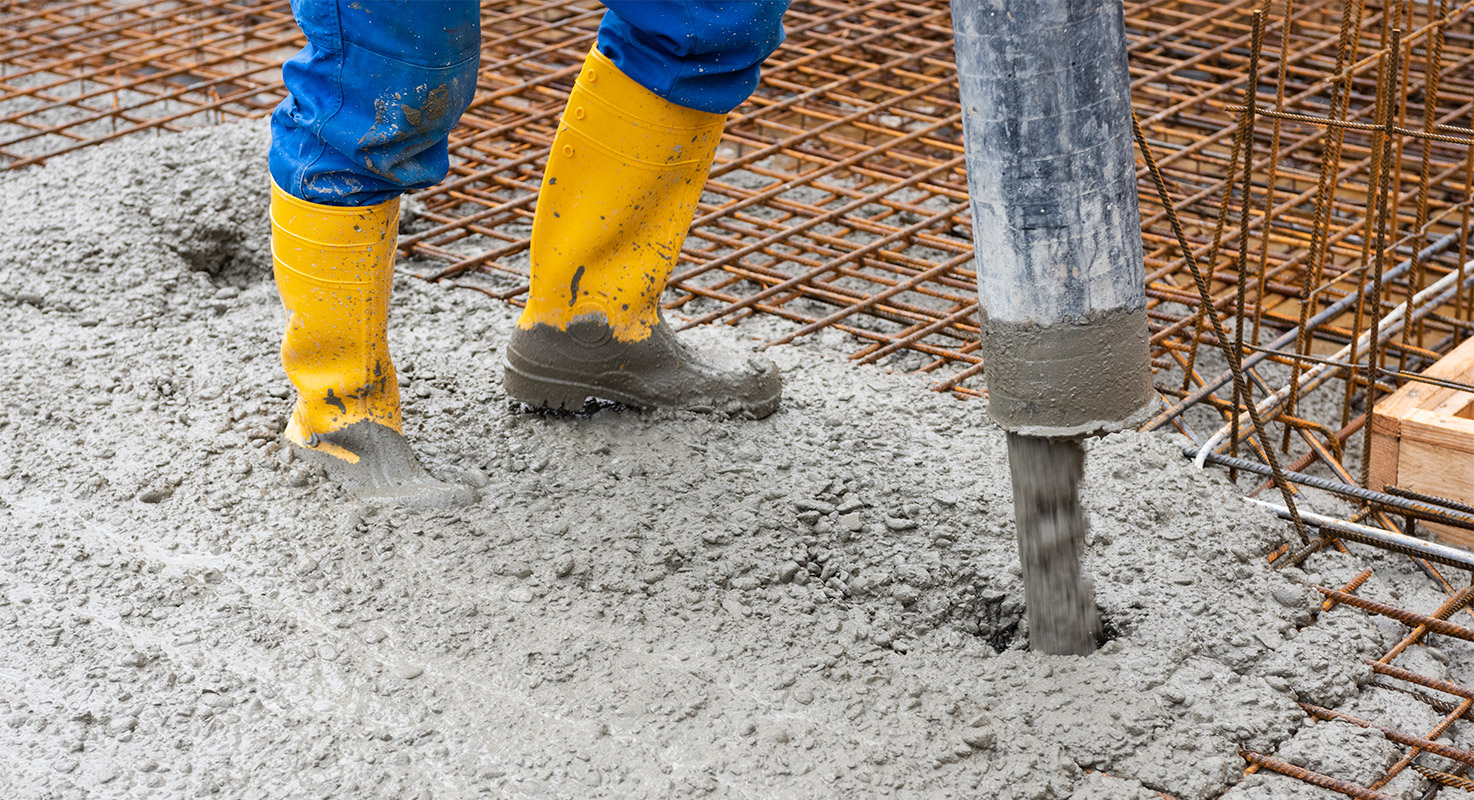 En betongarbetare gjuter betong över armeringsjärn.