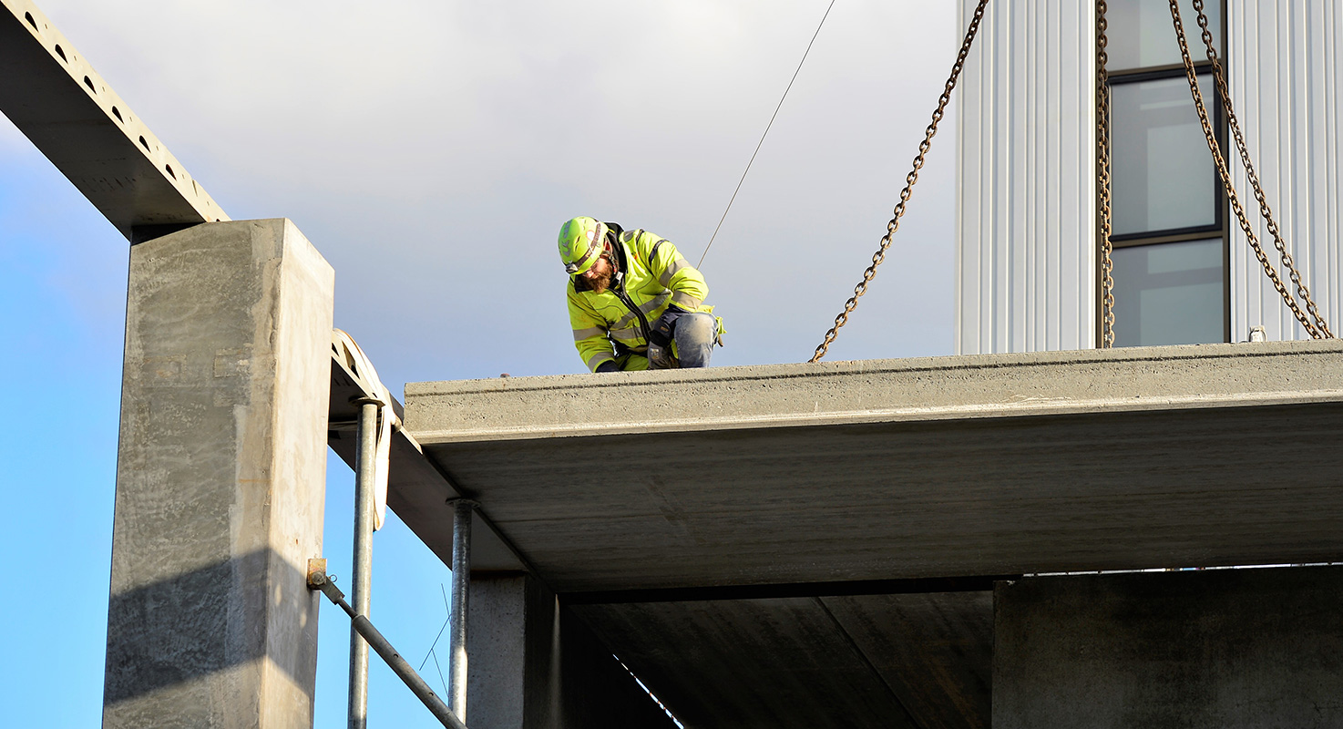 Betongarbetare arbetar med montering av ett betongelement på en byggarbetsplats.