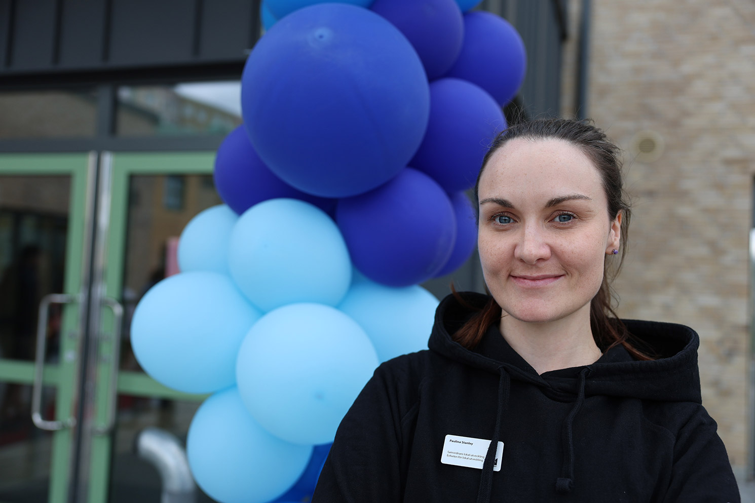 Paulina Stanley står intill blåa ballonger vid skolentrén