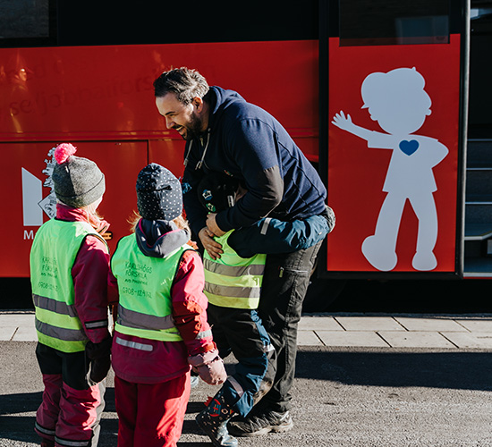 Barnskötaren Ilir Osmani som har kört förskolebussarna sedan 2013 är efterlängtad och möts av åtta förväntansfulla barn från Karlshögs förskola.