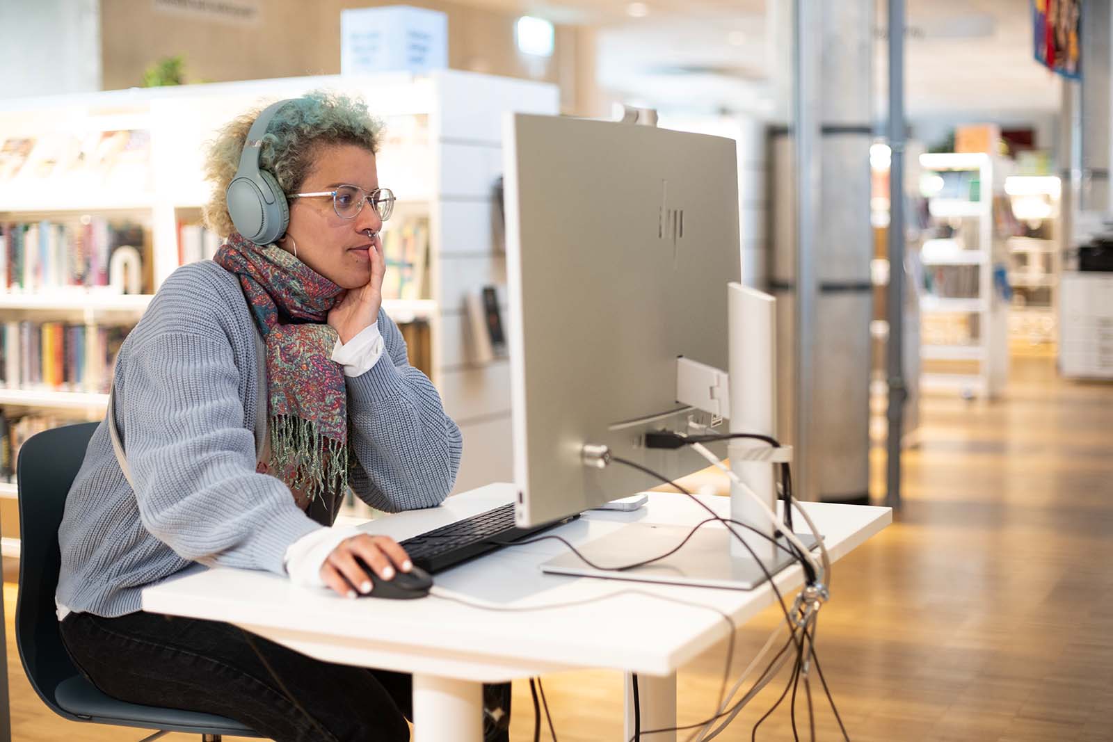 Kvinna vid dator i bibliotek.