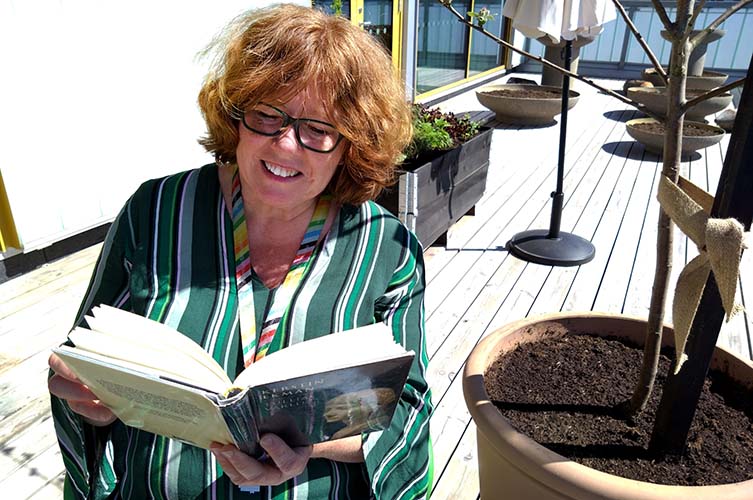 Sabina läser på terrassen på Rosengårdsbiblioteket.