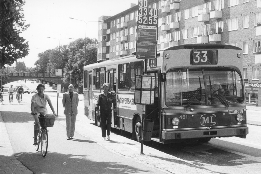 Svartvitt äldre fotografi över väg och stadsbebyggnad. 