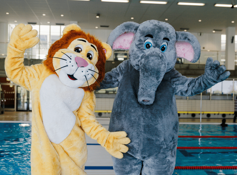 Hylliebadets maskotar Lejonet Leif och Elefanten Ella vinkar till kameran.
