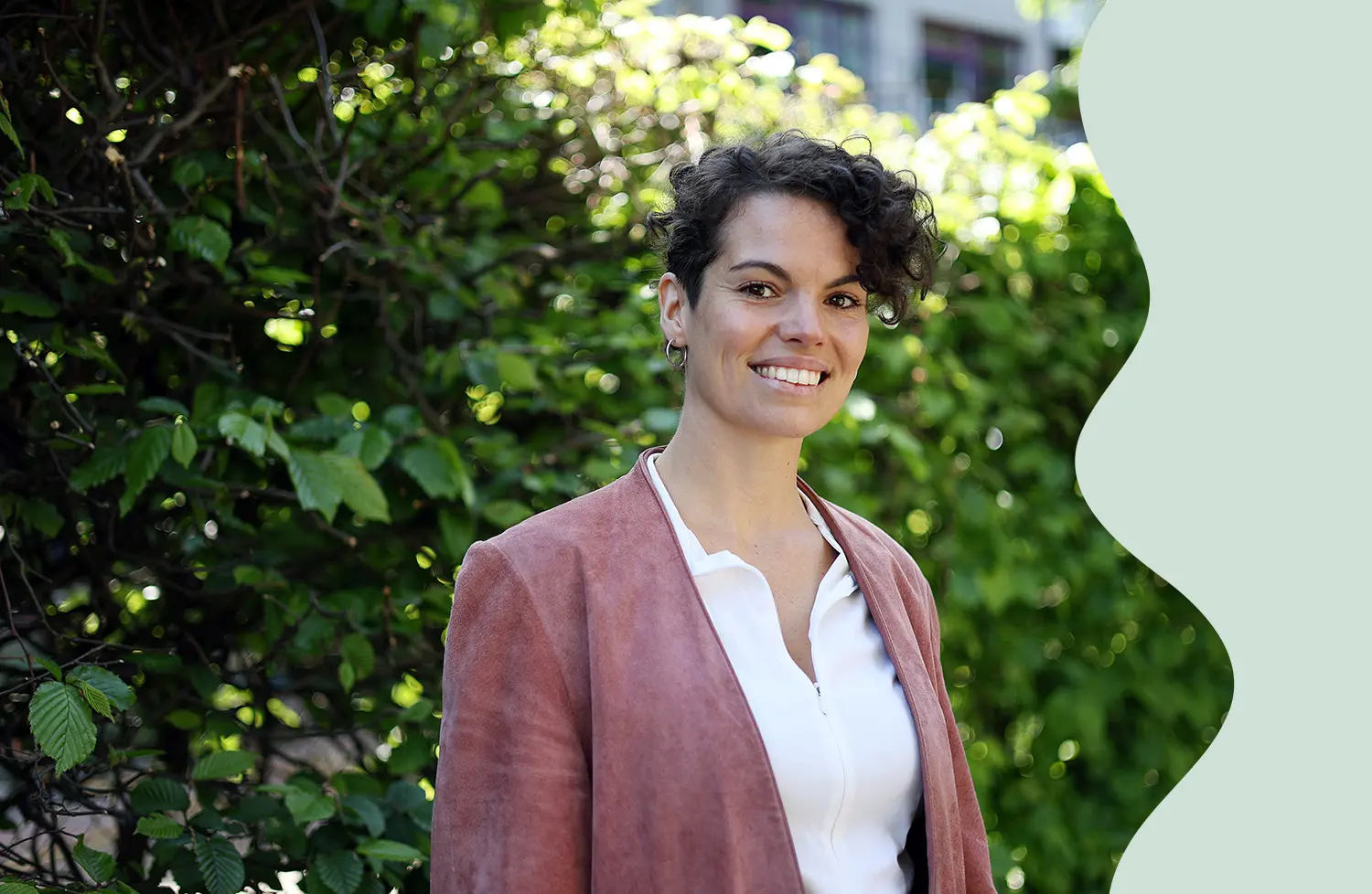 Mojra Blomberg har lockigt hår och röd kavaj.