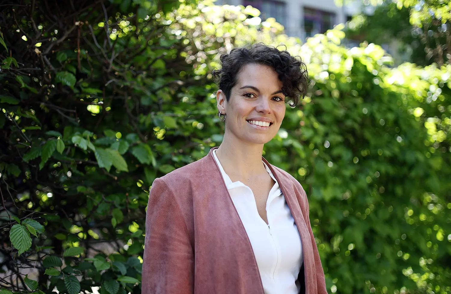 Mojra Blomberg har lockigt hår och röd kavaj.