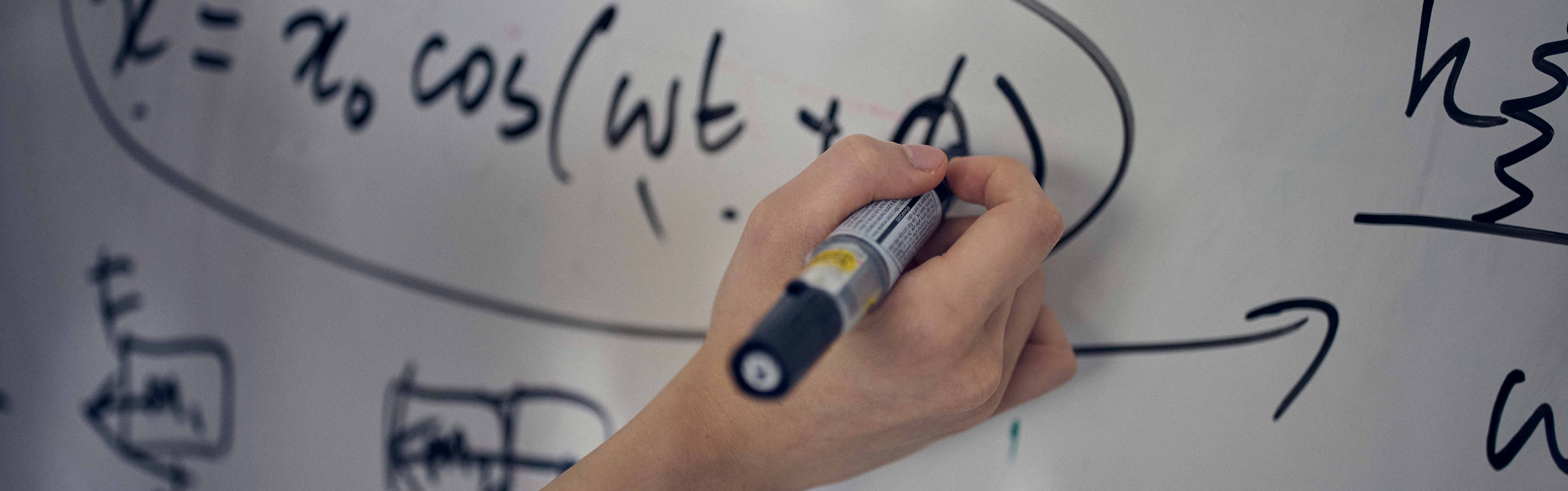 Hand som löser ett mattetal på en whiteboard.