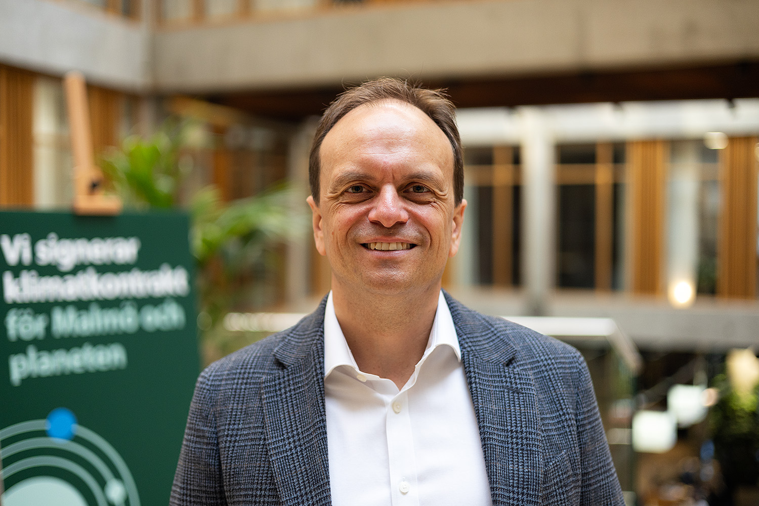 Mikkel Sjølin Kiil har kort brunt hår, grå kavaj och vit skjorta.