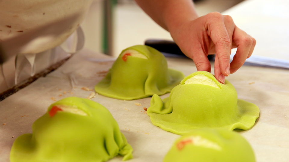 Plåt med fyra marsipanbakelsee, En hand jobbar med en av bakelserna